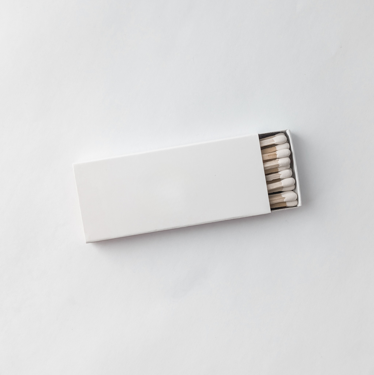 Open white matchbox with white-tipped candle matches.